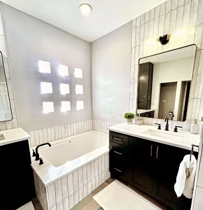 Completed bathroom with a glass block window, bath and dark vanity