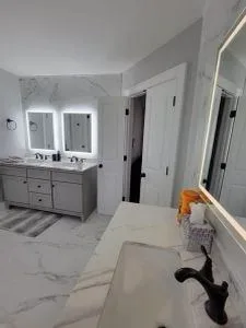 Completed bathroom with a double vanity and lit mirrors