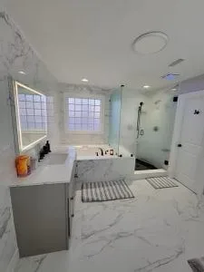 Completed bathroom with a bath, glass shower and lit mirror