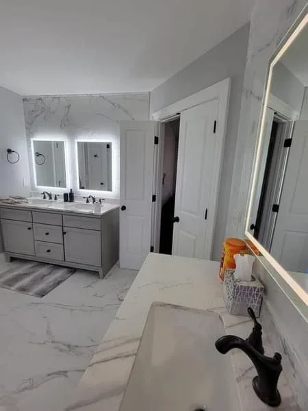Completed bathroom with a grey double vanity and lit mirrors