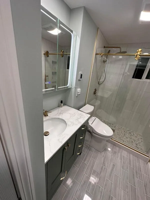 Completed bathroom with a vanity, toilet and tiled walls