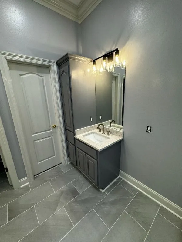 Completed bathroom vanity with wall lighting and panelled door