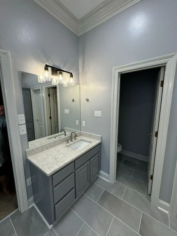 Completed bathroom with a stone topped vanity and mirror